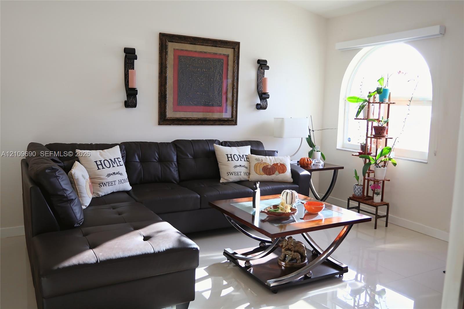 Living area featuring polished tile flooring and a prominent arched window