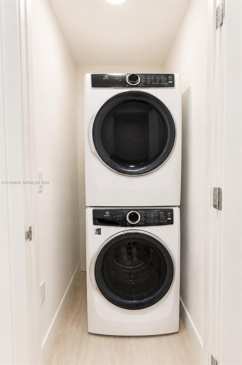 Laundry closet featuring a white, stackable front-loading washer and dryer set
