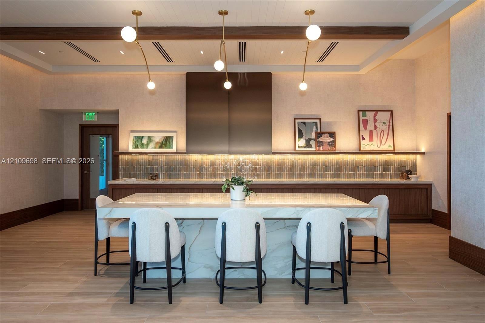 Kitchen featuring a stone-topped island with waterfall edges, custom wood cabinetry, a full-height metallic range hood, linear accent lighting, and wood-finish flooring