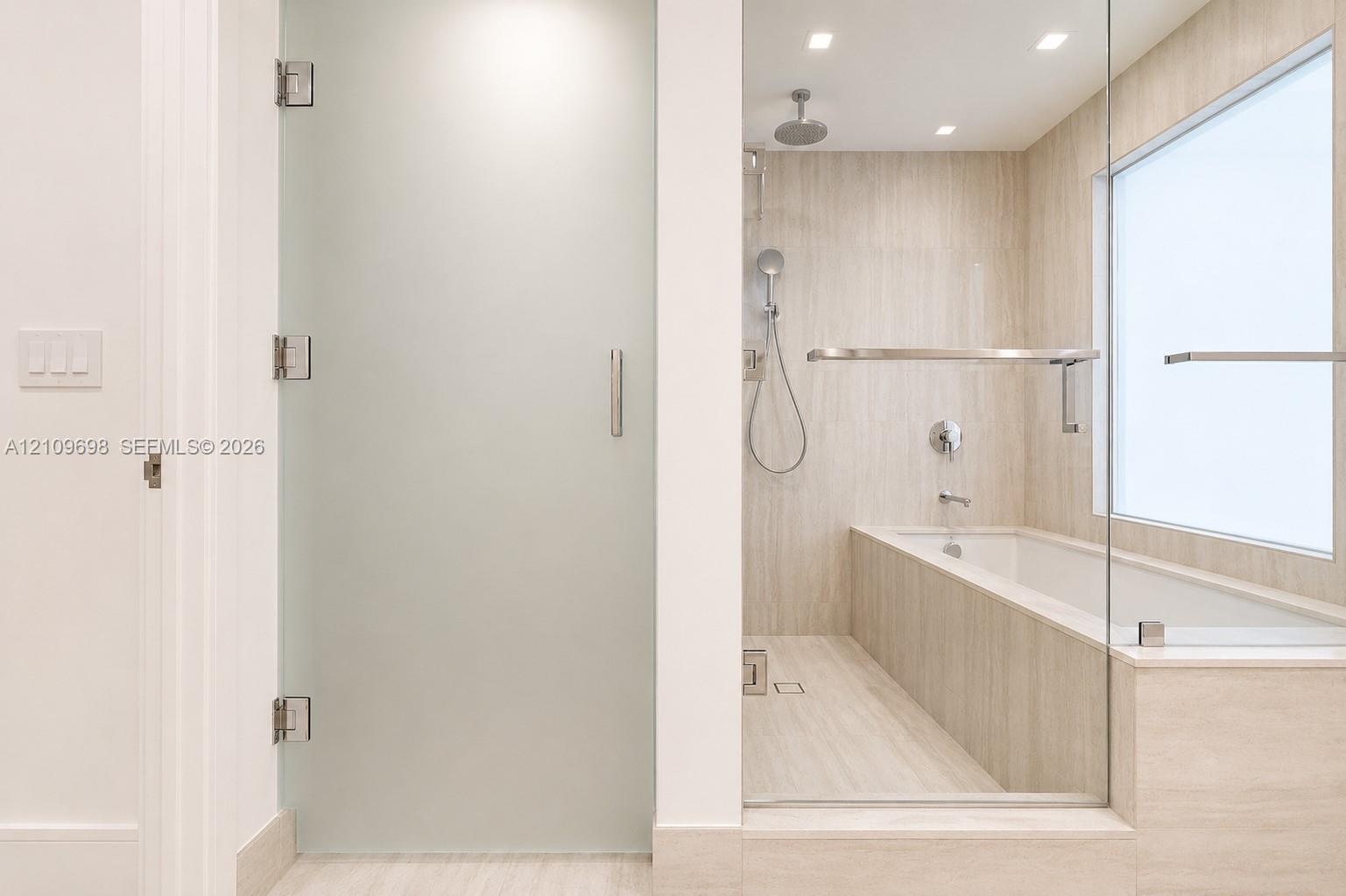 Bathroom featuring a frosted glass door, tile-surround soaking tub, wall-mounted shower fixture, frameless glass partition, and recessed lighting