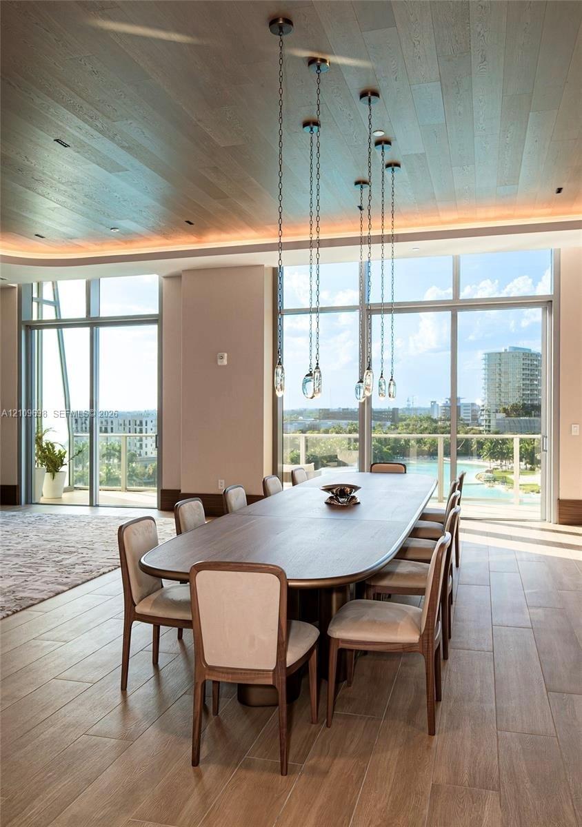 Floor-to-ceiling windows, wood-finish flooring, recessed perimeter ceiling lighting, and suspended glass pendant lighting