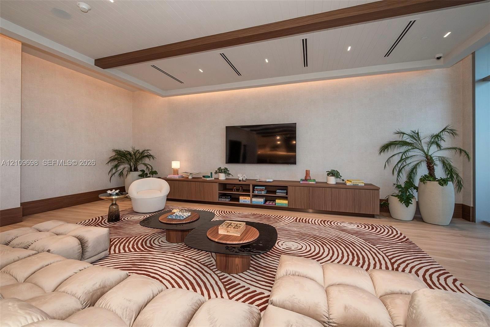 Tray ceiling with recessed wood-trim detailing, linear lighting, integrated cabinetry with wood finish, and wood-finish flooring