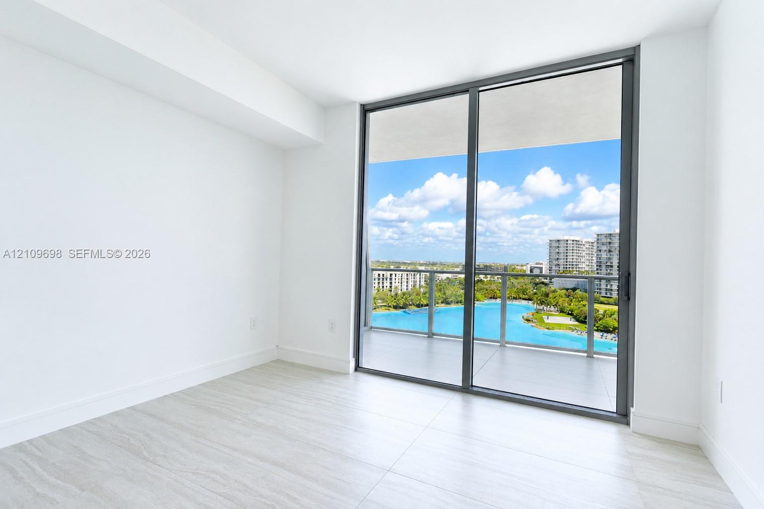 Interior space featuring floor-to-ceiling sliding glass doors, neutral tile flooring, and a covered balcony with a glass railing