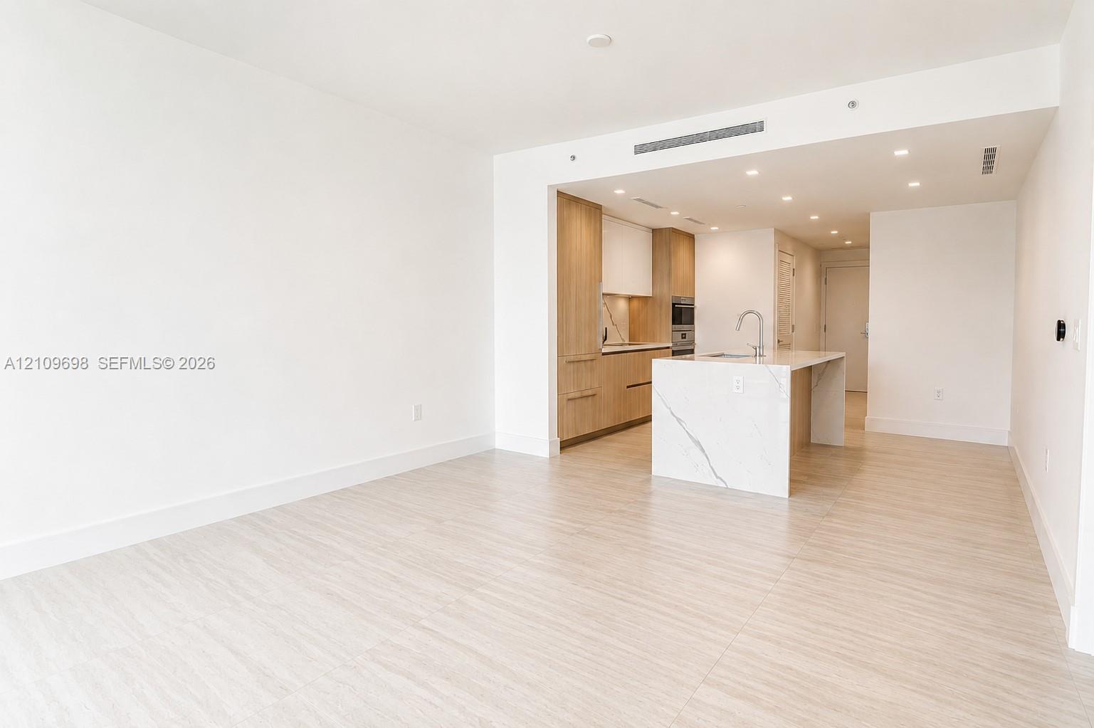 Open-concept space with light-toned wood-finish flooring and recessed ceiling lighting