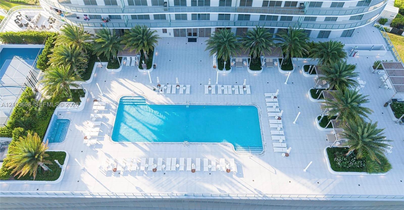 Swimming pool with an integrated spa, paved sun deck, and mature palm landscaping