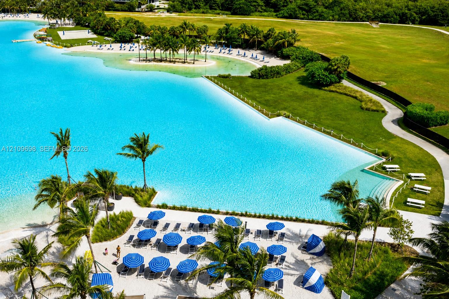 Man-made lagoon featuring a white sand beach, extensive perimeter landscaping, walking paths, and concrete terraced stairs leading to the water