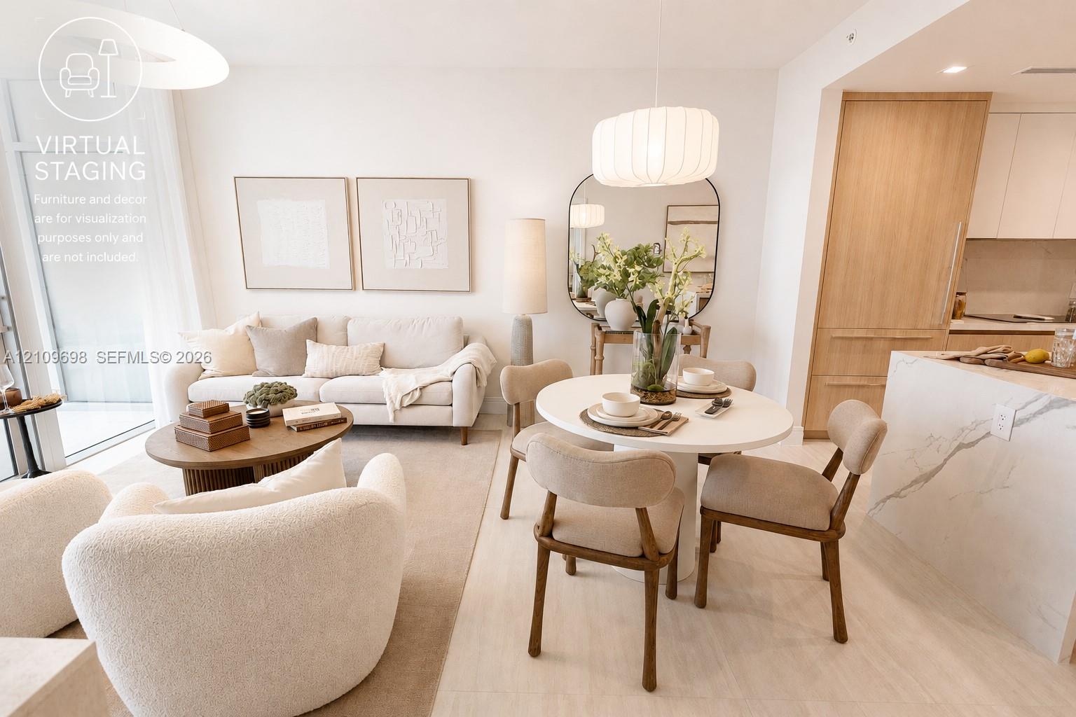Open-concept interior featuring light-toned wood-finish flooring, a waterfall-edge stone island, built-in floor-to-ceiling cabinetry, and modern pendant lighting