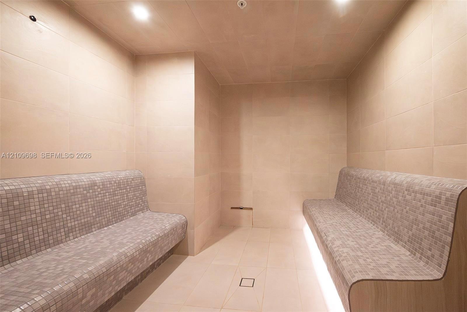 Sauna featuring floor-to-ceiling tile, dual built-in benches with mosaic tile finish, under-bench ambient lighting, and recessed ceiling lighting