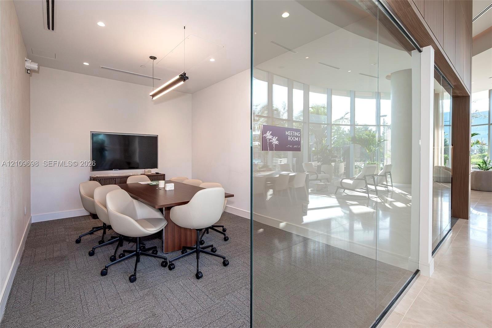 Meeting room featuring floor-to-ceiling glass wall, recessed lighting, linear pendant light fixture, and neutral carpeted flooring