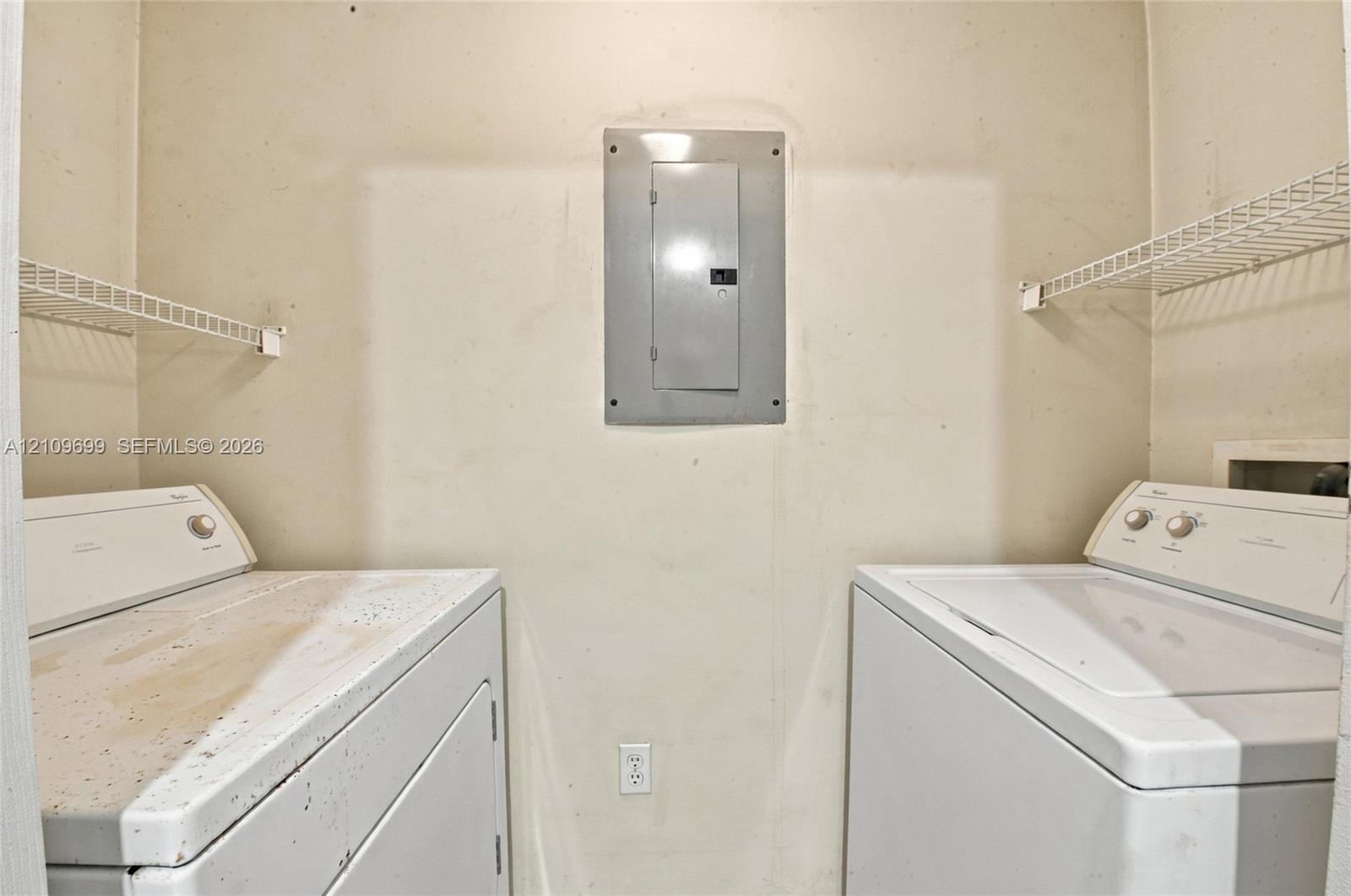 Utility space featuring wall-mounted wire shelving and a centrally located electrical panel
