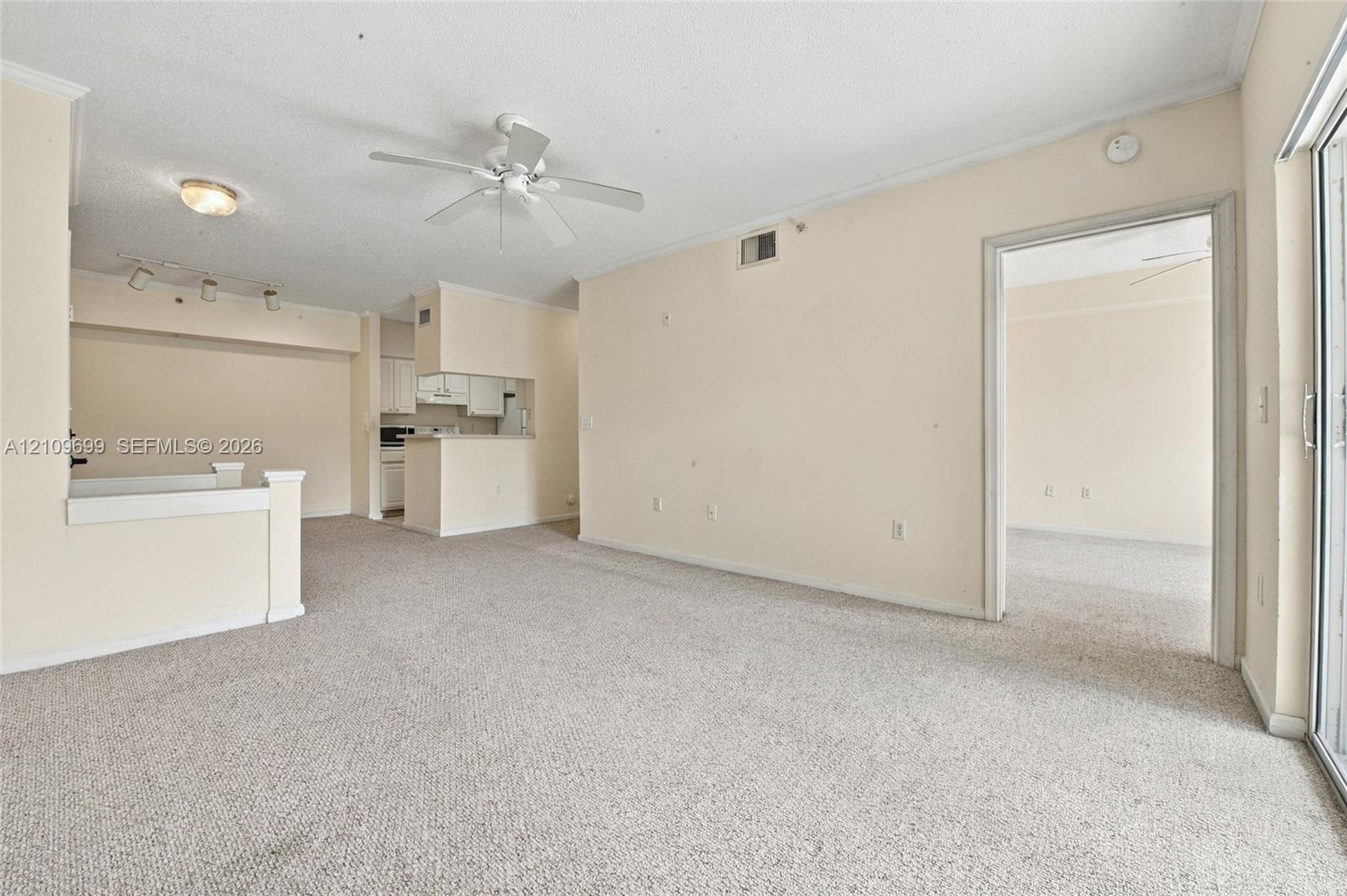 Open-concept interior featuring wall-to-wall carpeting, a ceiling fan, sliding glass door, and recessed track lighting