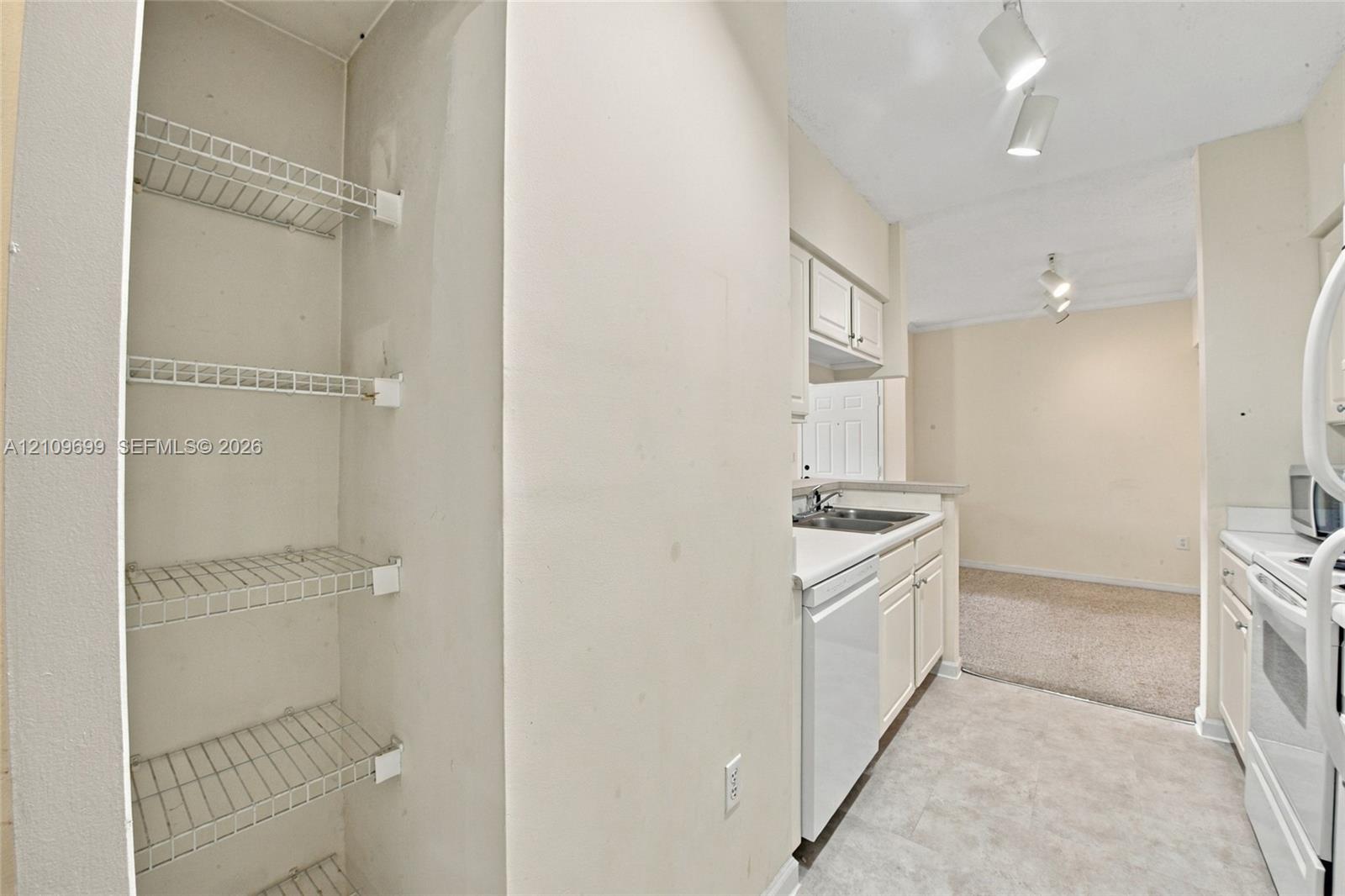 Kitchen featuring white cabinetry, wire shelving, tile flooring, and integrated track lighting