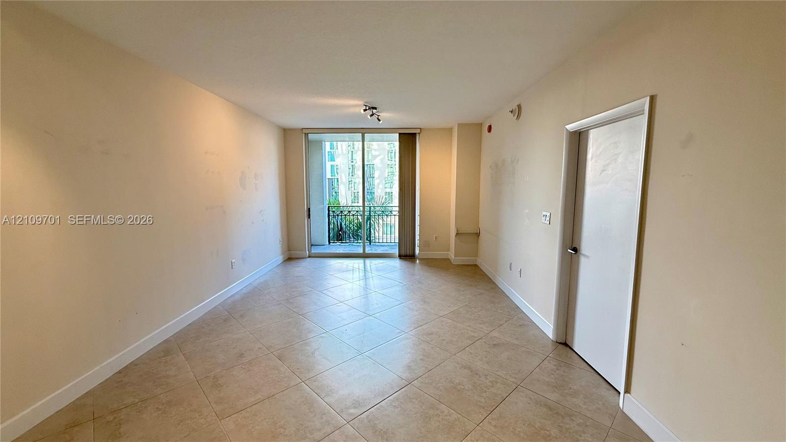 Neutral-toned interior space featuring diagonal-set tile flooring, multi-track sliding glass doors, and recessed ceiling lighting Neutral-toned interior space featuring diagonal-set tile flooring, multi-track sliding glass doors, and recessed ceiling lighting