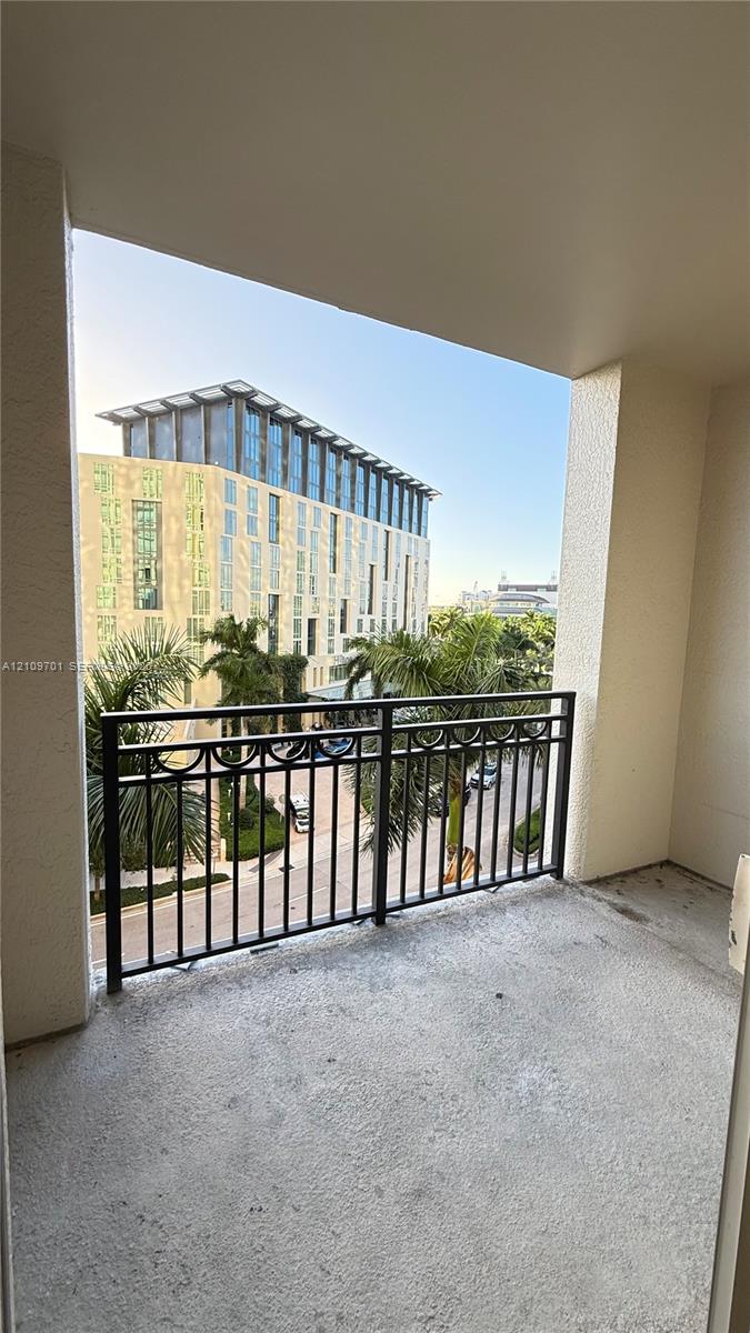 Covered balcony featuring concrete flooring and a decorative black metal railing