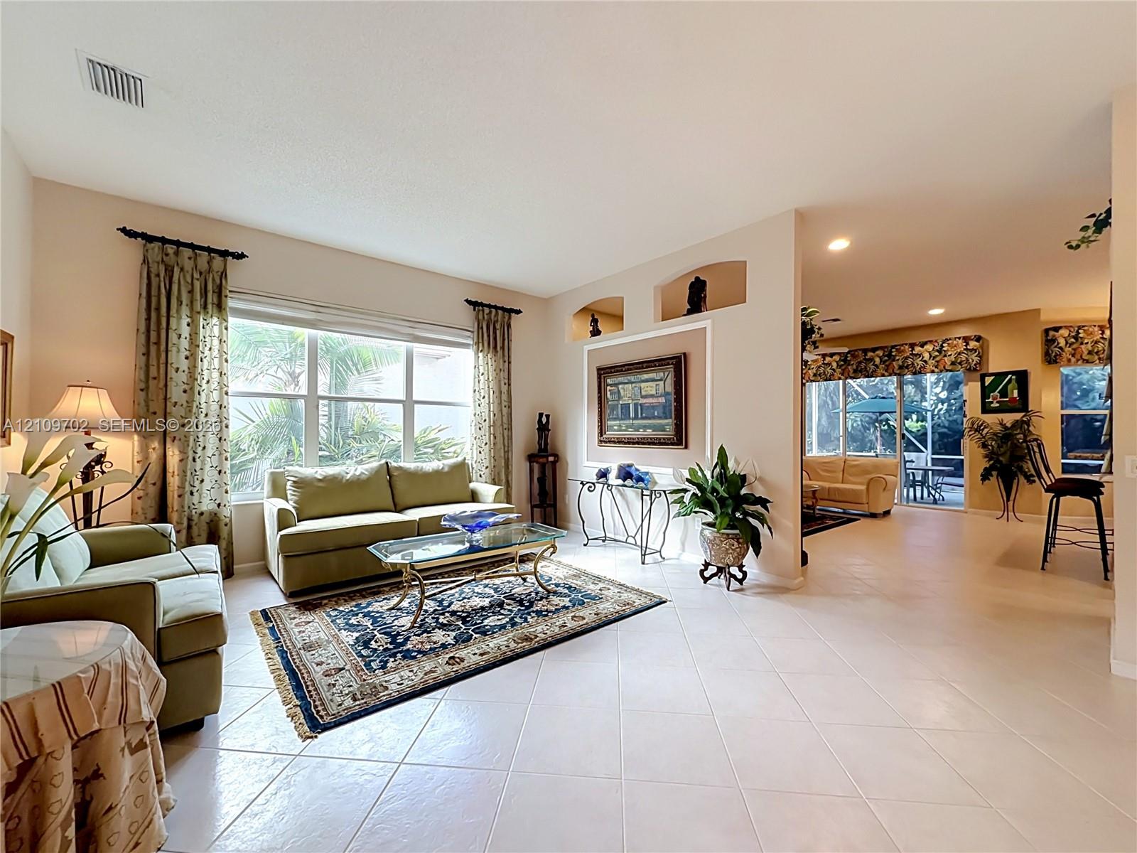 Living area featuring large windows, recessed wall niches, tile flooring, and sliding glass doors