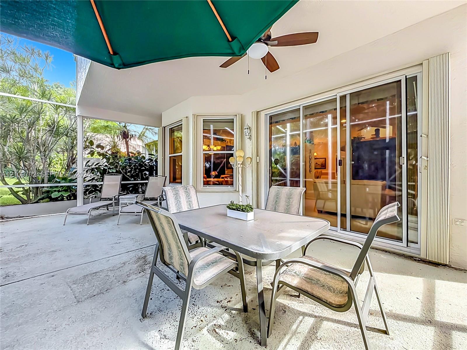 Screened-in covered lanai featuring a concrete floor, built-in ceiling fan, and multi-panel sliding glass doors