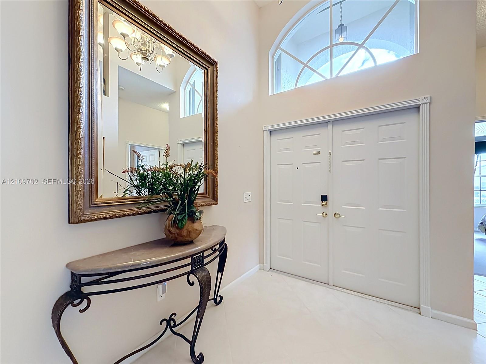 Double-door entry featuring a large arched transom window, high ceilings, and tile flooring
