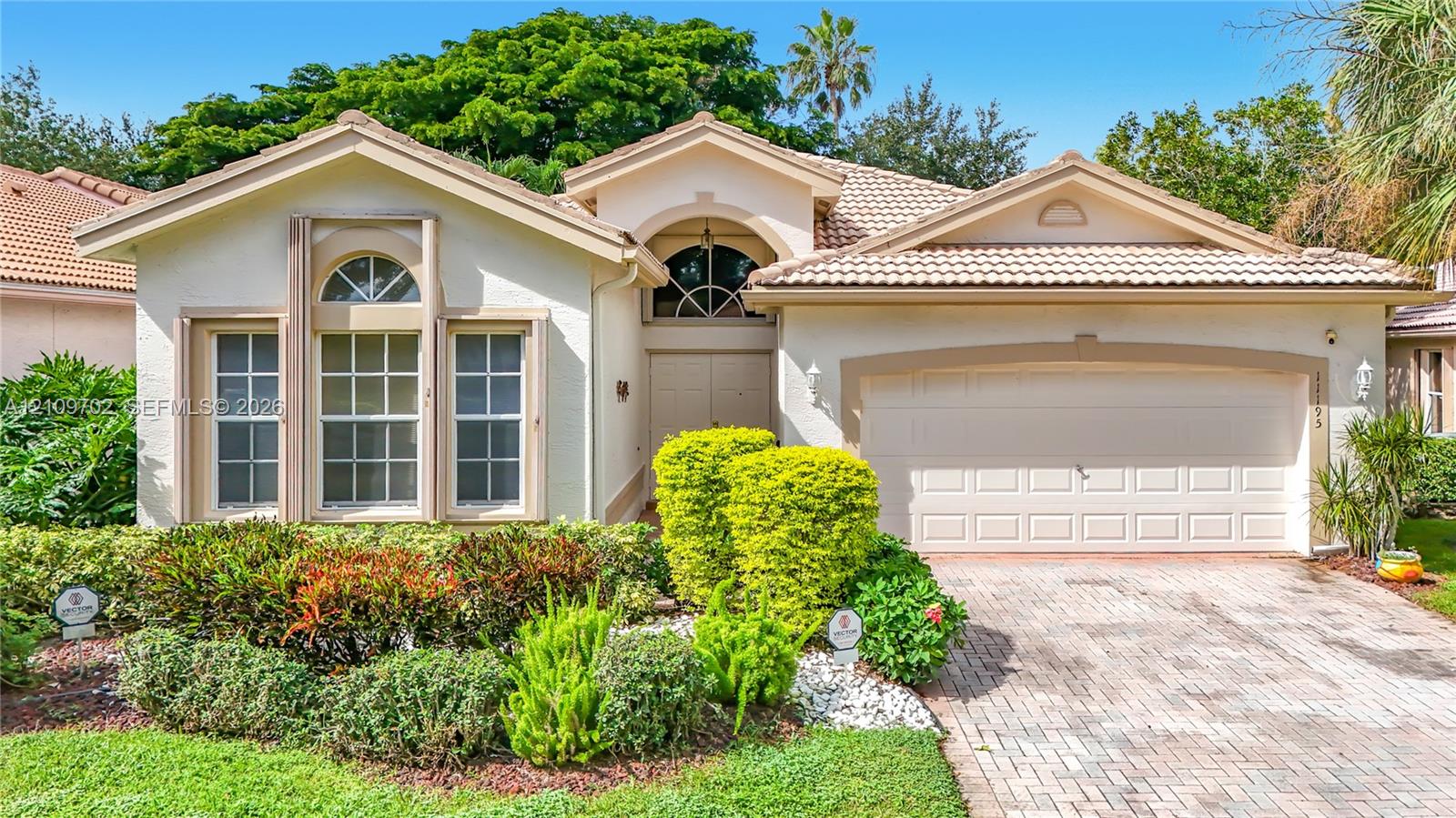 Stucco exterior featuring arched windows, tile roof, and a paved stone driveway Stucco exterior featuring arched windows, tile roof, and a paved stone driveway