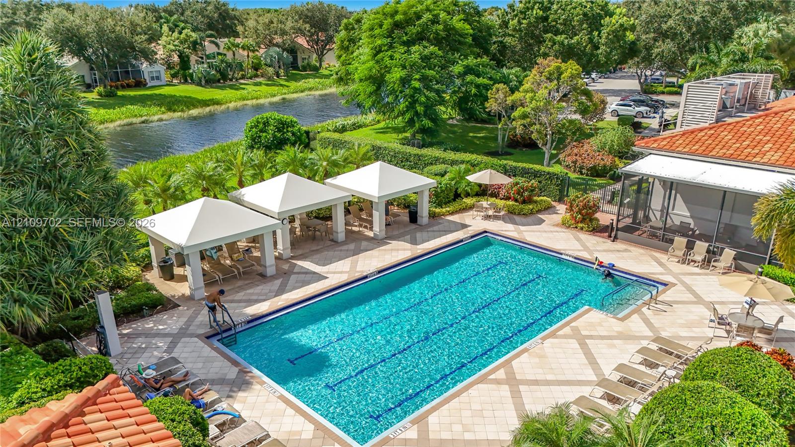 Swimming pool with lap lanes, tiled pool deck, multiple covered pavilions, terracotta roof tiles, and water feature