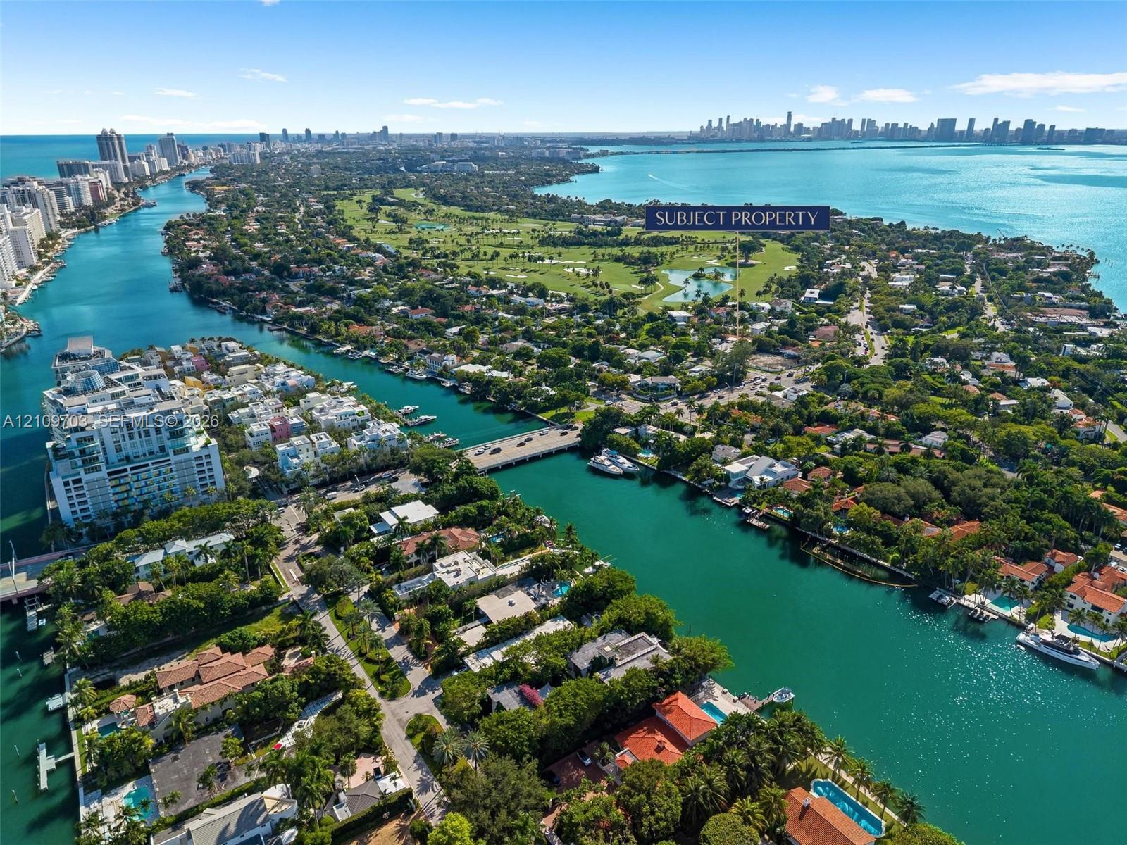 Aerial perspective of a coastal residential area featuring deep-water canal access, proximity to a golf course, and a backdrop of open bay waters
