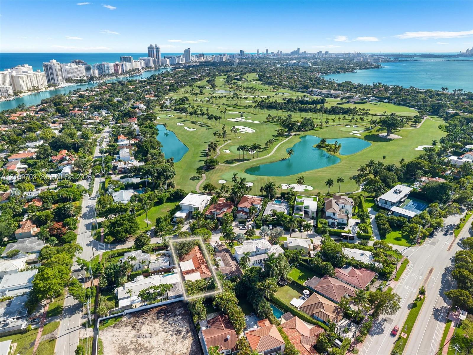 Aerial perspective of a property lot featuring mature landscaping and a tiled roof structure, positioned within a coastal metropolitan landscape