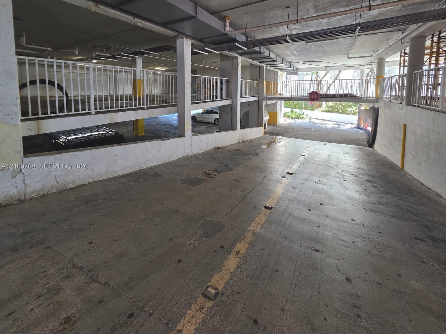 Multi-level parking structure featuring a concrete ramp, steel railings, and overhead lighting