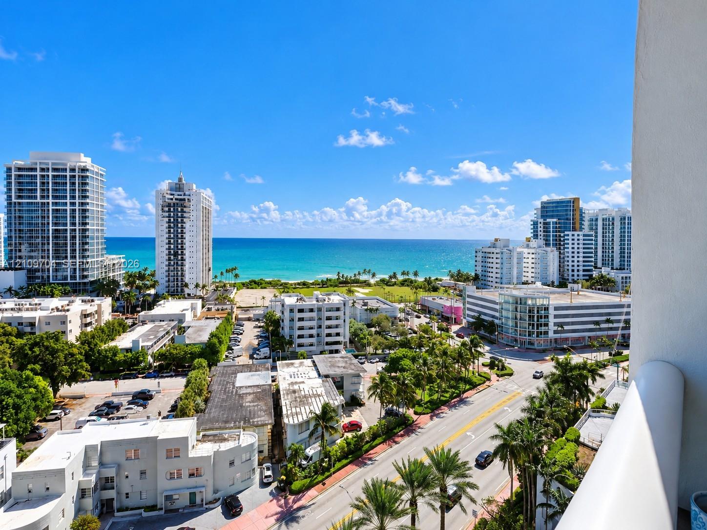 Elevated balcony featuring a white railing and expansive coastal scenery including ocean, sandy shoreline, and metropolitan architecture
