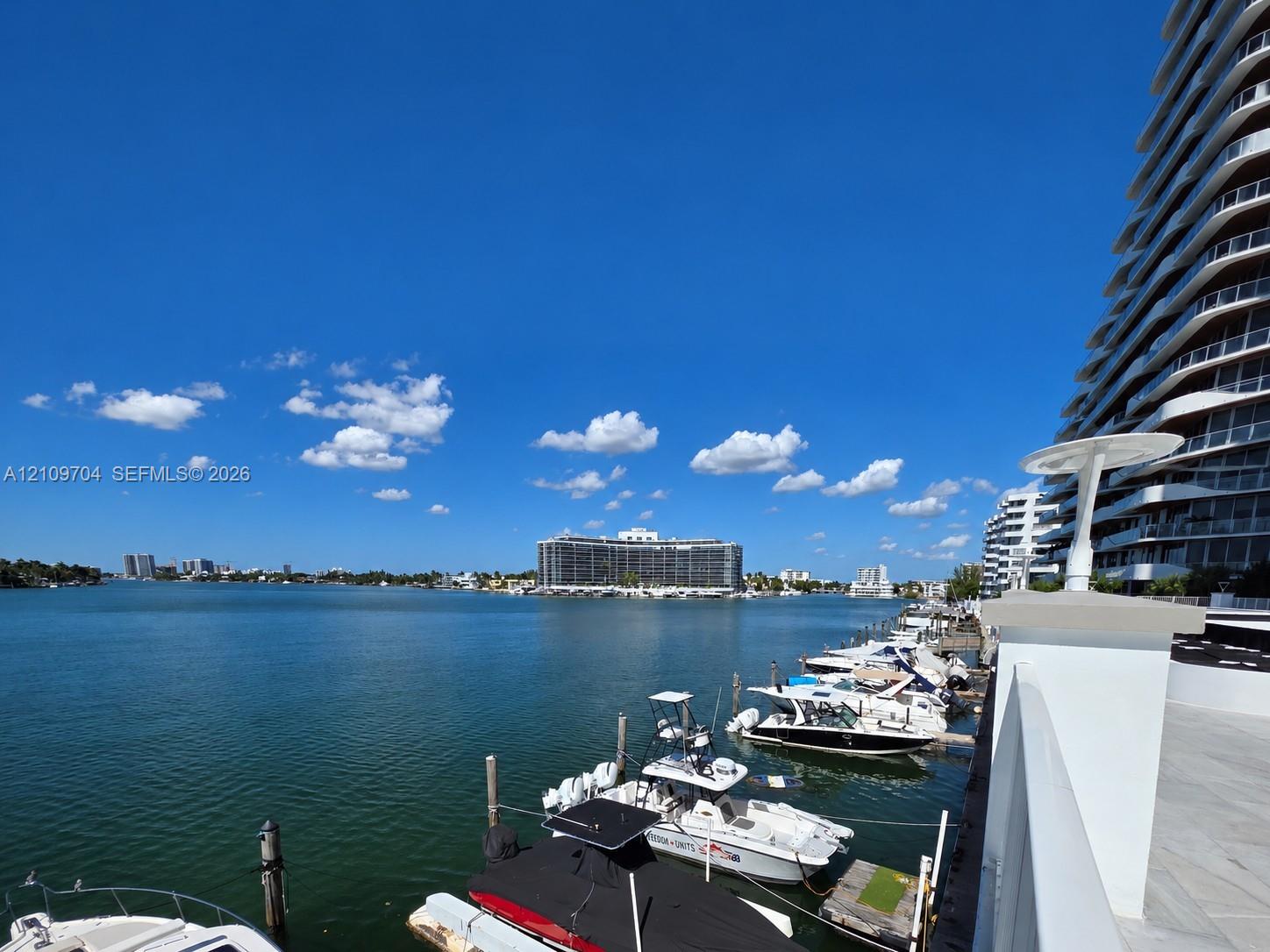 Waterfront property featuring a private boat slip, dockside power pedestals, concrete seawall, and stone-finished decking