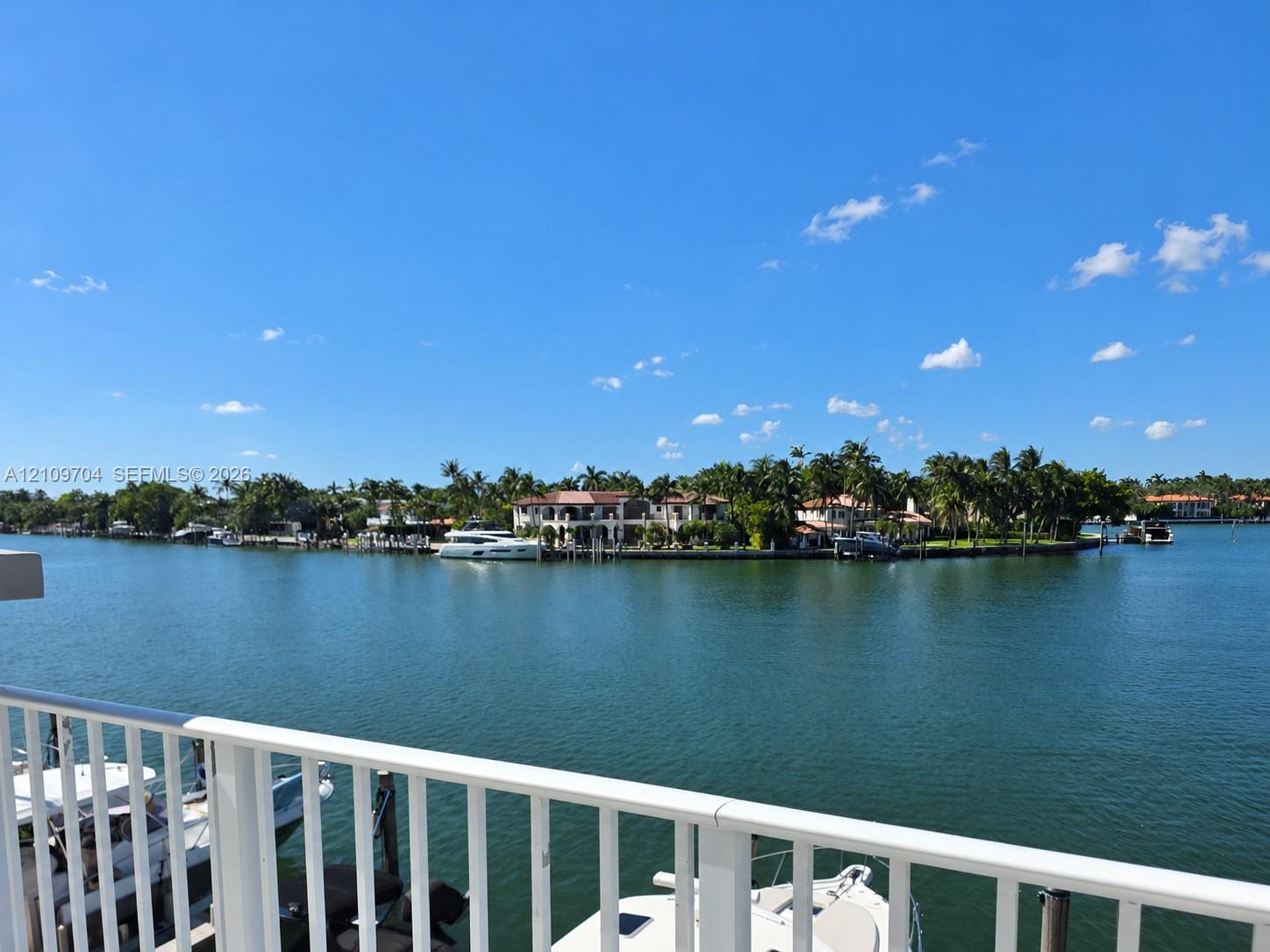 Waterfront property featuring a private boat slip, white metal railing, and direct waterway access