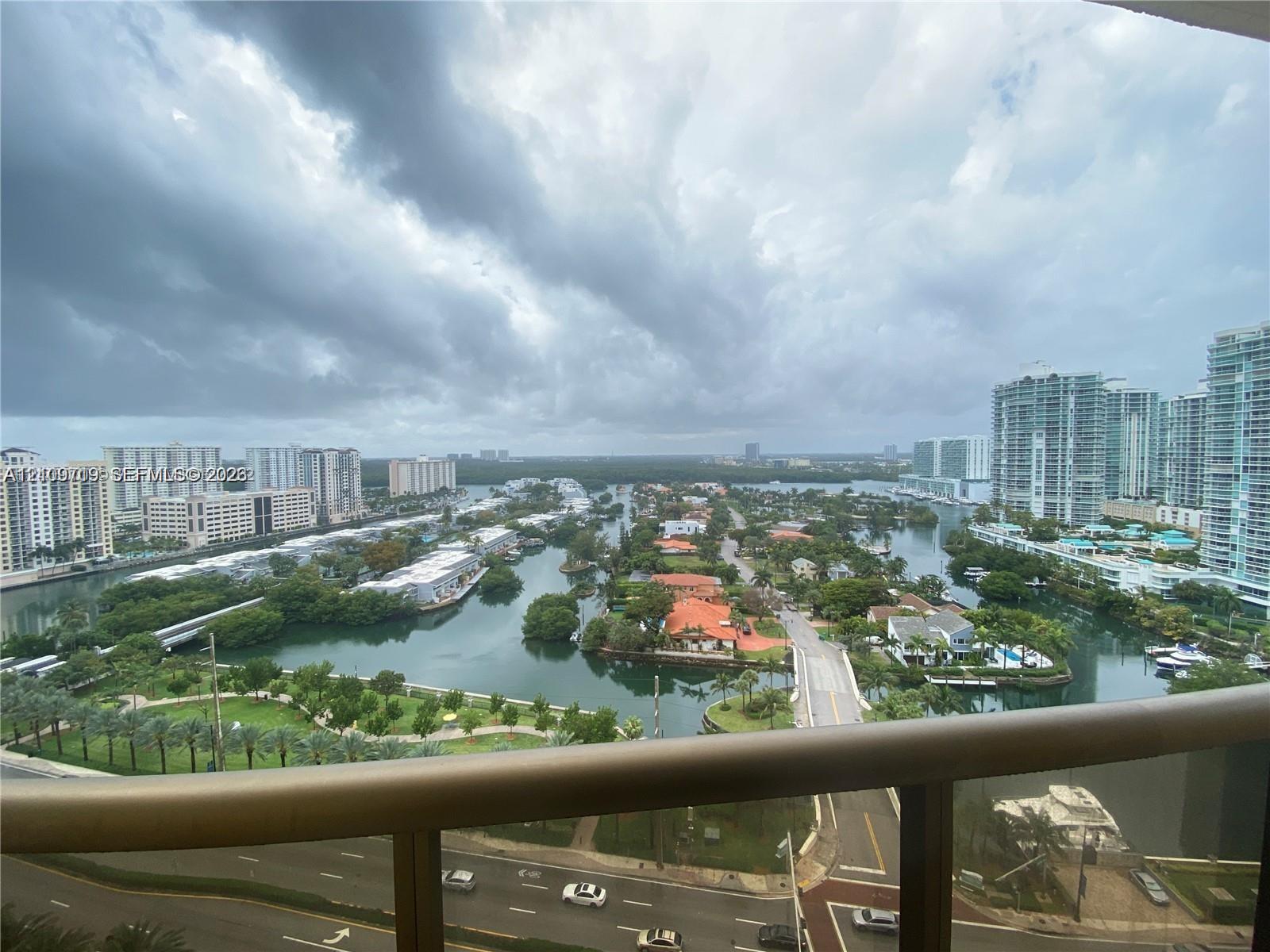 Balcony featuring a metal railing with panoramic imagery of a canal system, urban high-rises.