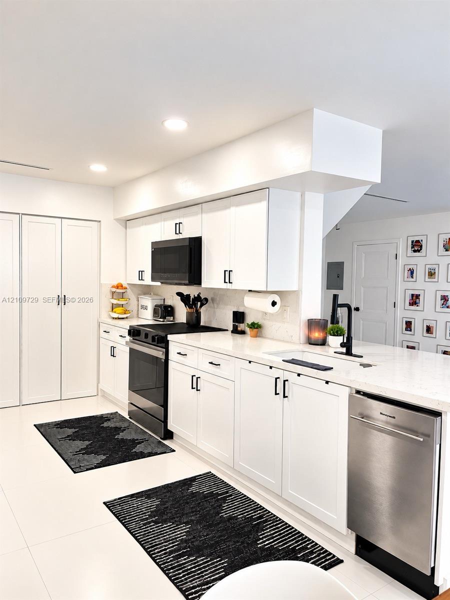 Kitchen featuring white cabinetry with matte black hardware, stone-finish countertops, recessed lighting, and a stainless steel dishwasher
