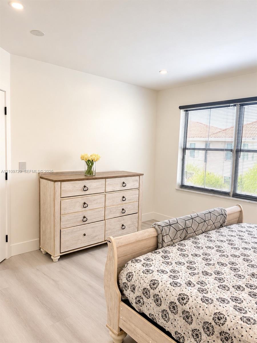 Neutral-toned interior featuring wood-finish flooring, recessed lighting, and a large window with dark-toned frames