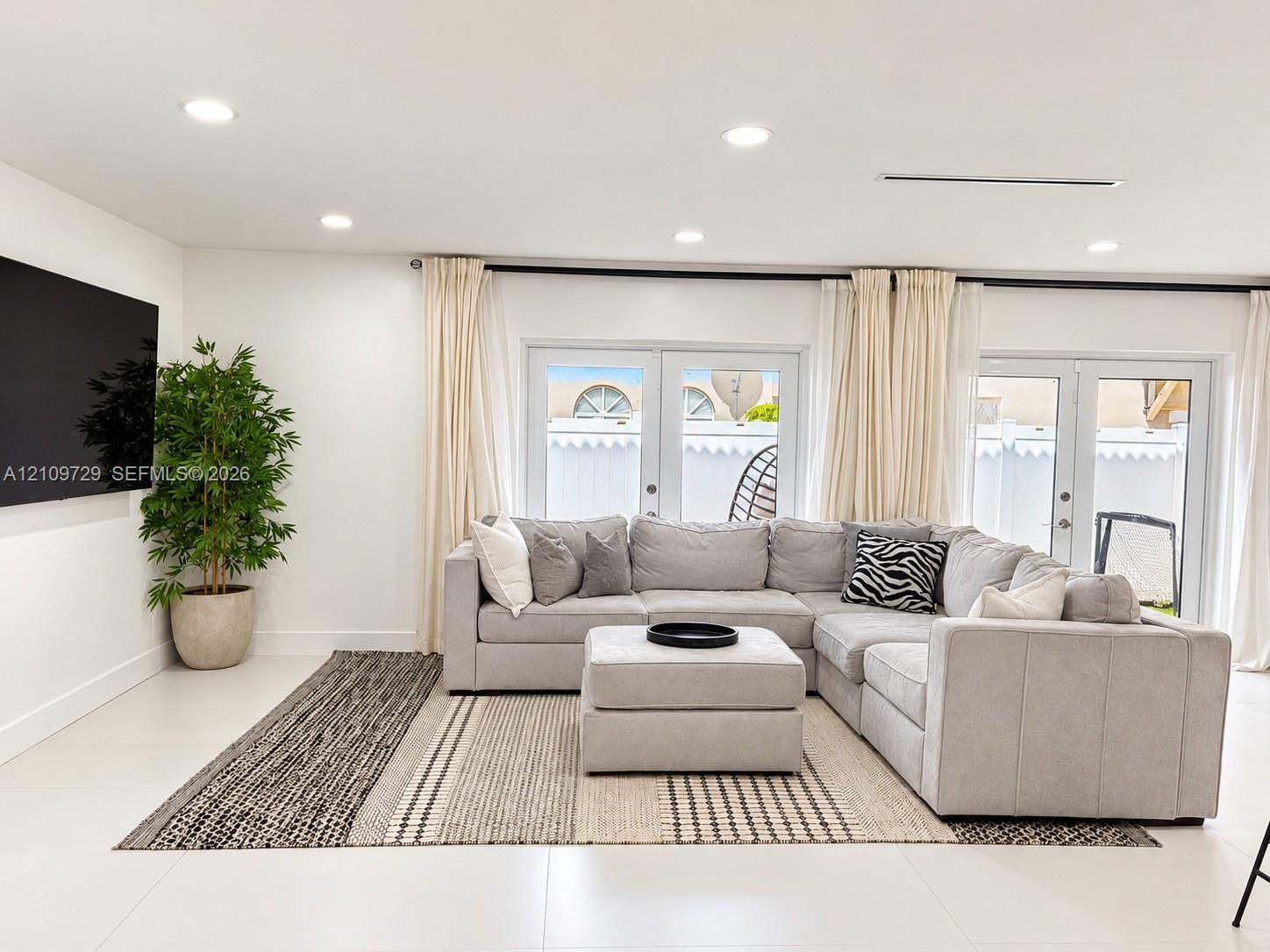 Open-concept space featuring recessed lighting, large-format tile flooring, and dual glass-panel patio doors