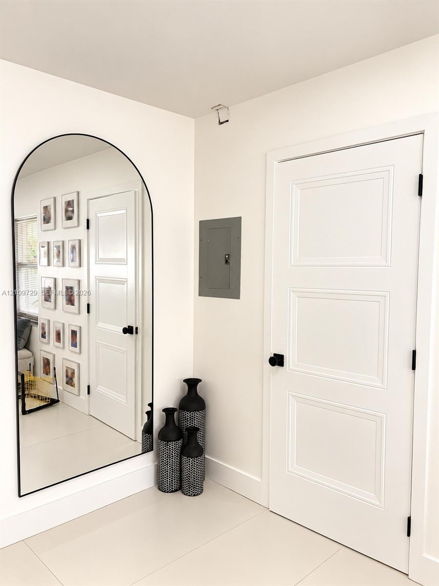 Arched wall mirror with a black metal frame, three-panel interior door with matte black hardware, and smooth-finish flooring