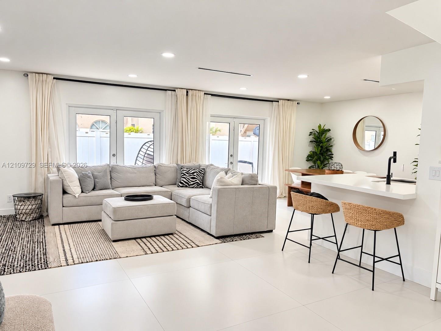 Open-concept interior featuring large-format tile flooring, recessed lighting, and dual sets of French doors