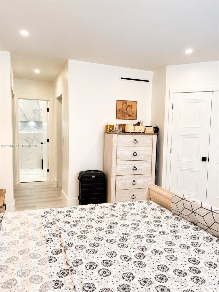 Recessed ceiling lighting, wood-finish flooring, and white paneled doors with matte black hardware