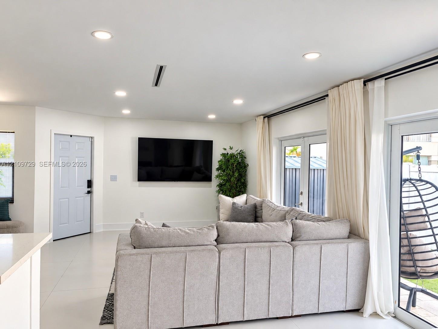 Open-concept interior featuring large-format tile flooring, recessed lighting, and double-glass paneled doors providing exterior access
