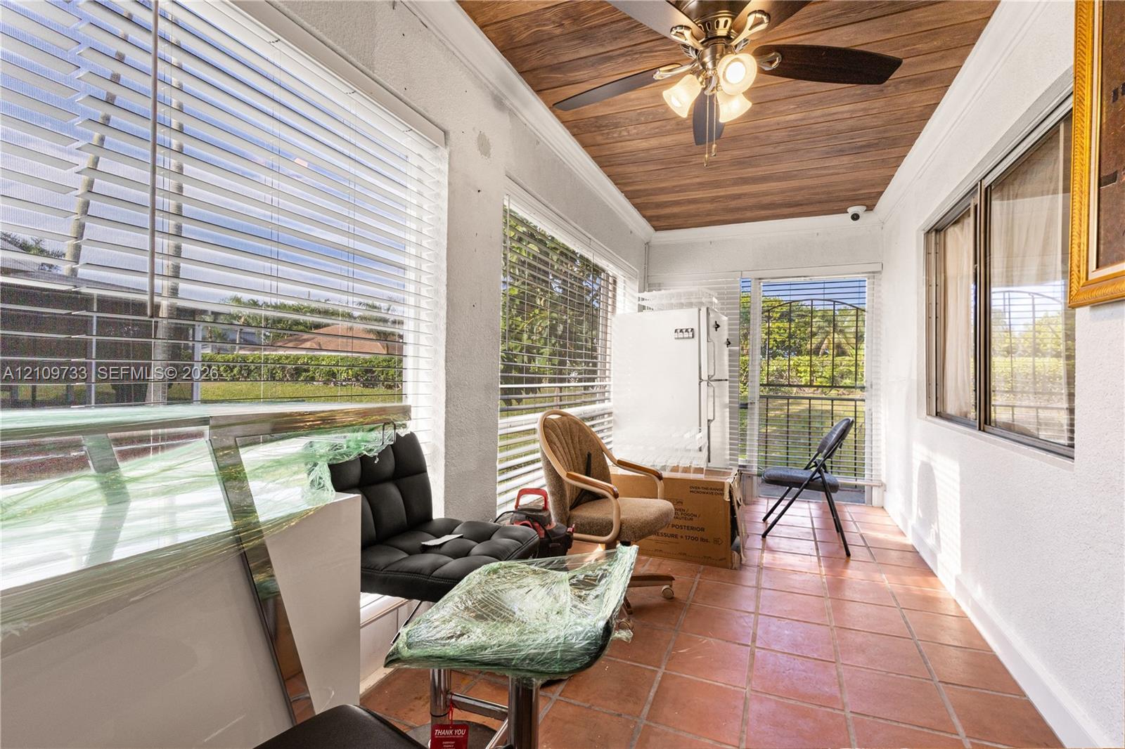 Enclosed patio featuring wood-finish ceiling paneling, ceramic tile flooring, a ceiling fan with integrated lighting, and expansive windows