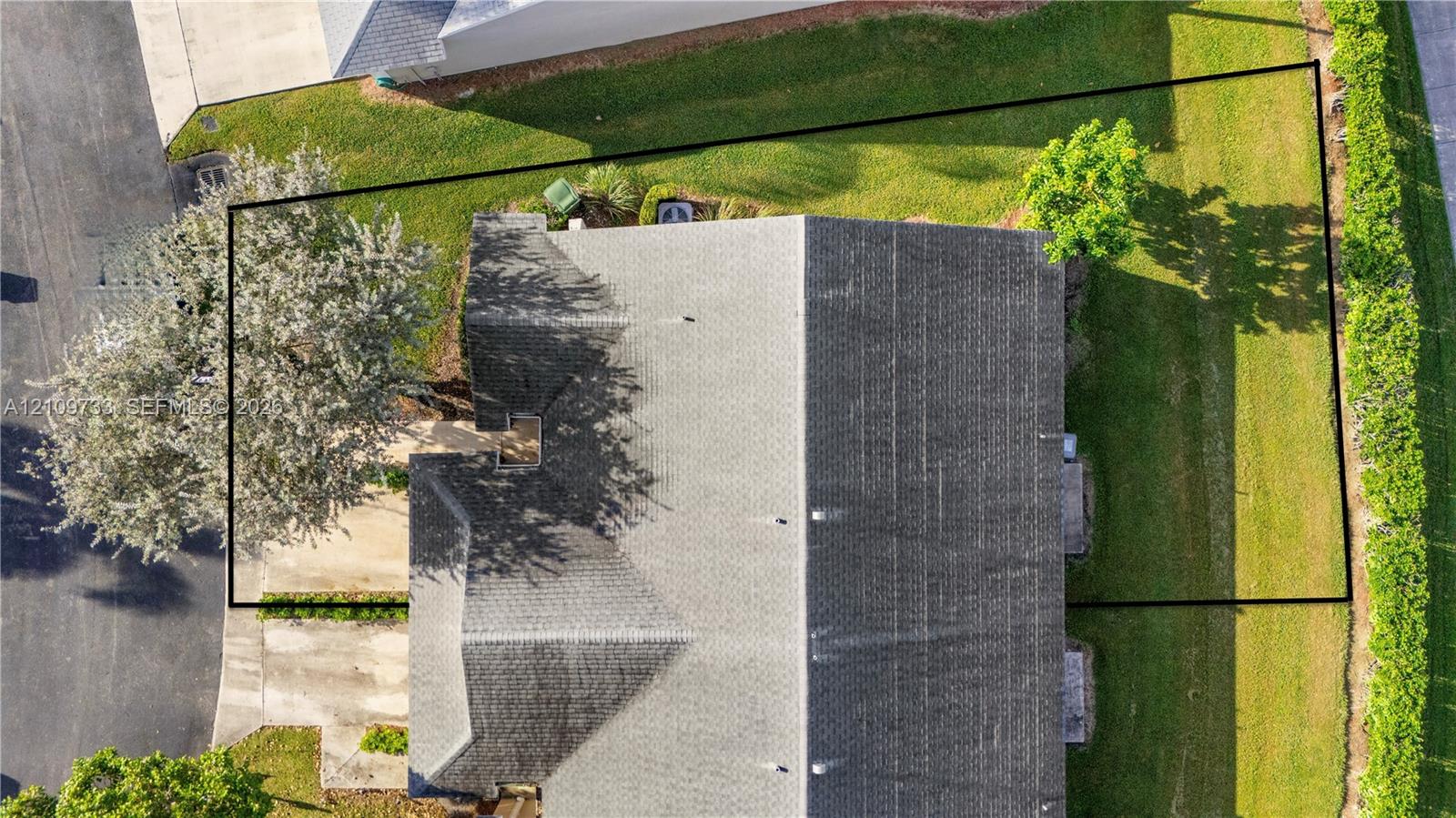 Aerial perspective highlighting a lot boundary, expansive lawn area, mature trees, and shingled roofline Aerial perspective highlighting a lot boundary, expansive lawn area, mature trees, and shingled roofline