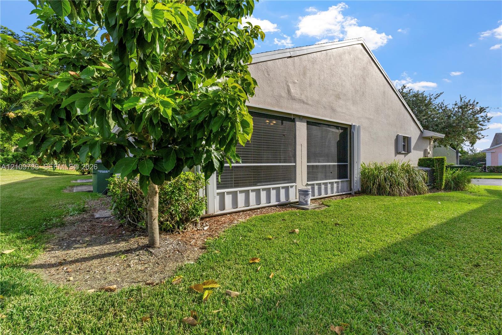 Stucco exterior featuring a screened-in patio, concrete-tile roofing, and established landscaping Stucco exterior featuring a screened-in patio, concrete-tile roofing, and established landscaping