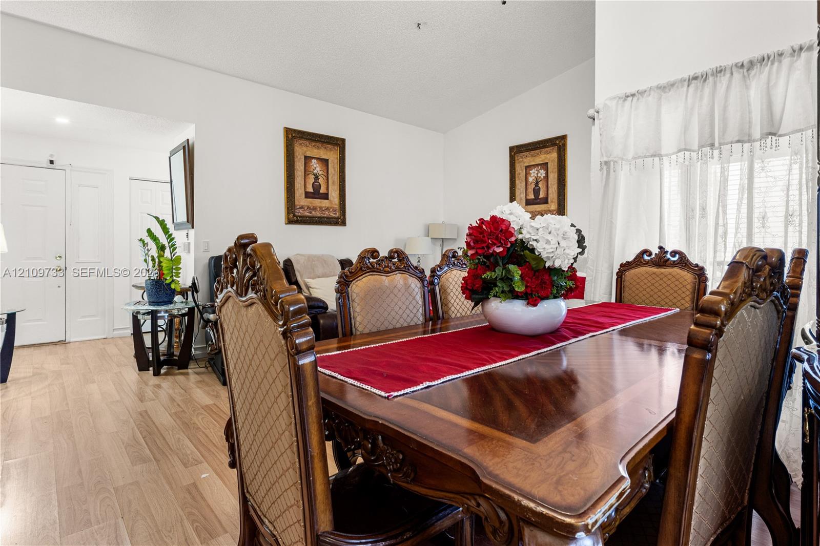 Open-concept living space featuring wood-finish flooring, vaulted ceilings, and natural light via window treatments Open-concept living space featuring wood-finish flooring, vaulted ceilings, and natural light via window treatments
