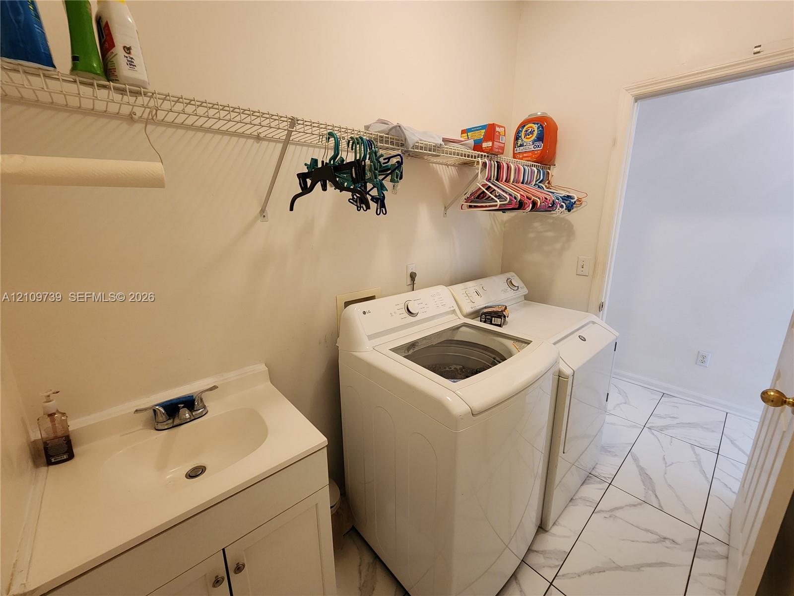 Utility room featuring large-format tile flooring, built-in vanity cabinet with integrated sink, and wire shelving