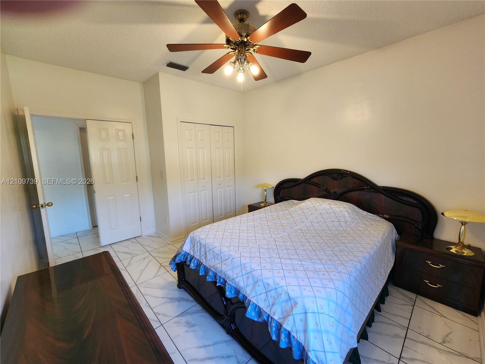 Tile flooring with stone-pattern finish, ceiling fan with integrated lighting, and double-door closet