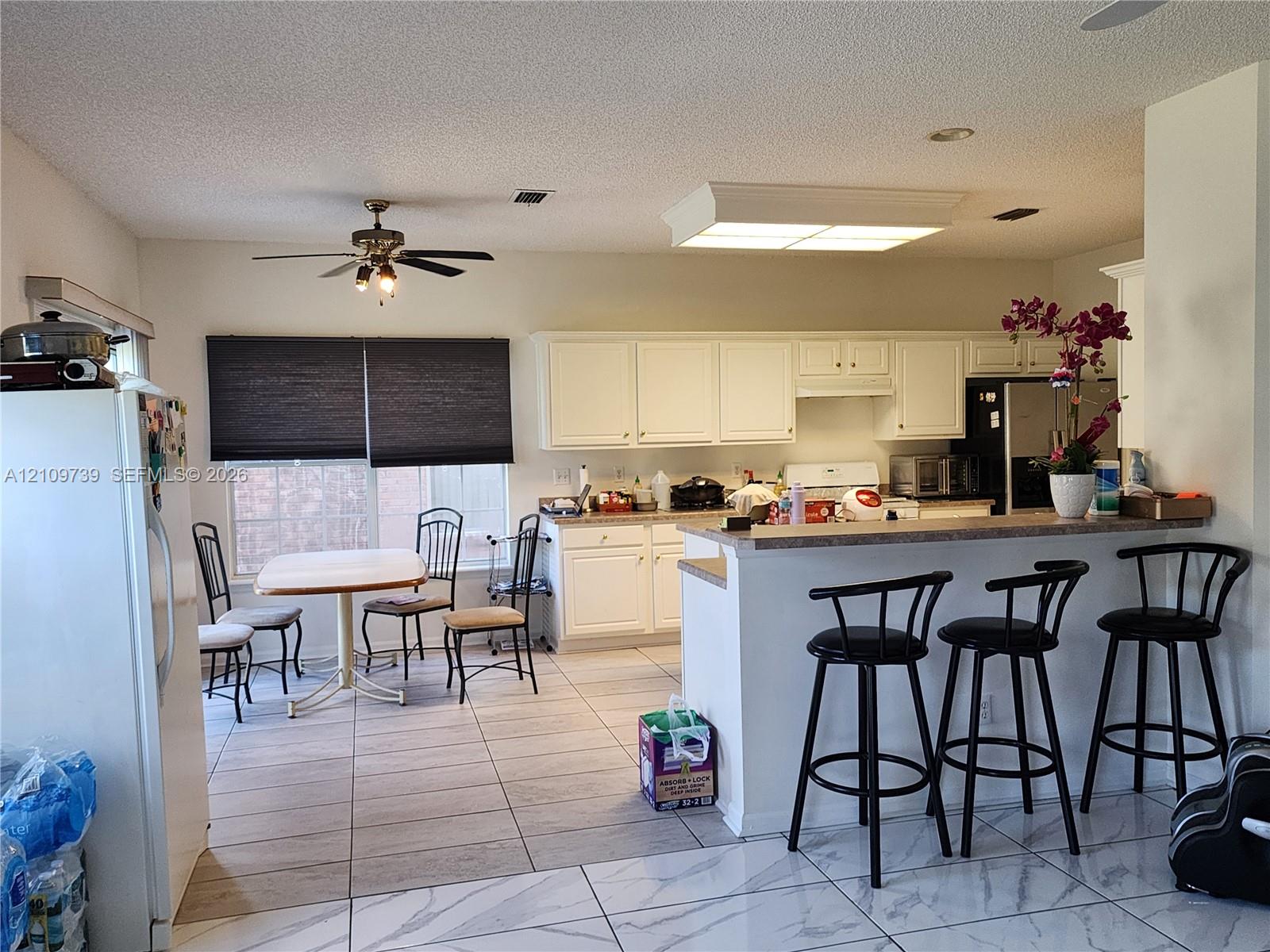 Kitchen featuring white cabinetry, a breakfast bar, recessed lighting, and large-format floor tiling