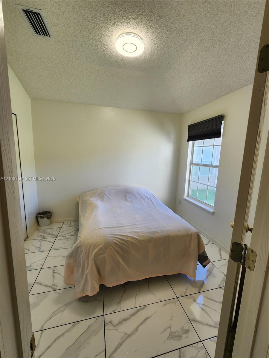 Large-format stone-style tile flooring, dual-pane window, and flush-mount ceiling lighting