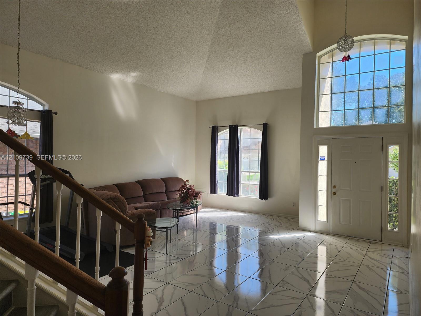 Vaulted ceilings, expansive stone-finish tile flooring, arched windows, and a multi-lite front door with sidelights Vaulted ceilings, expansive stone-finish tile flooring, arched windows, and a multi-lite front door with sidelights
