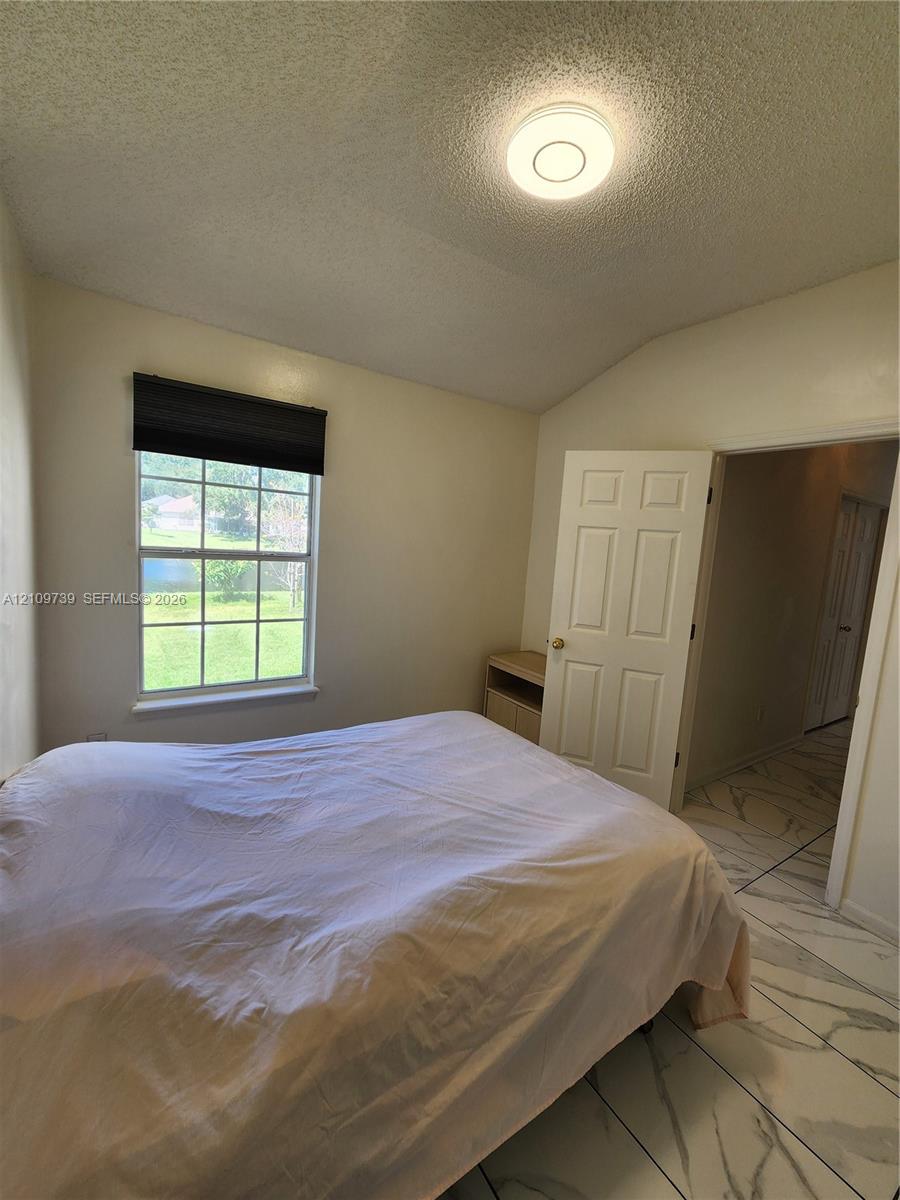 Vaulted ceilings, large-format tile flooring with marble-style veining, and a single-pane window with grid detailing