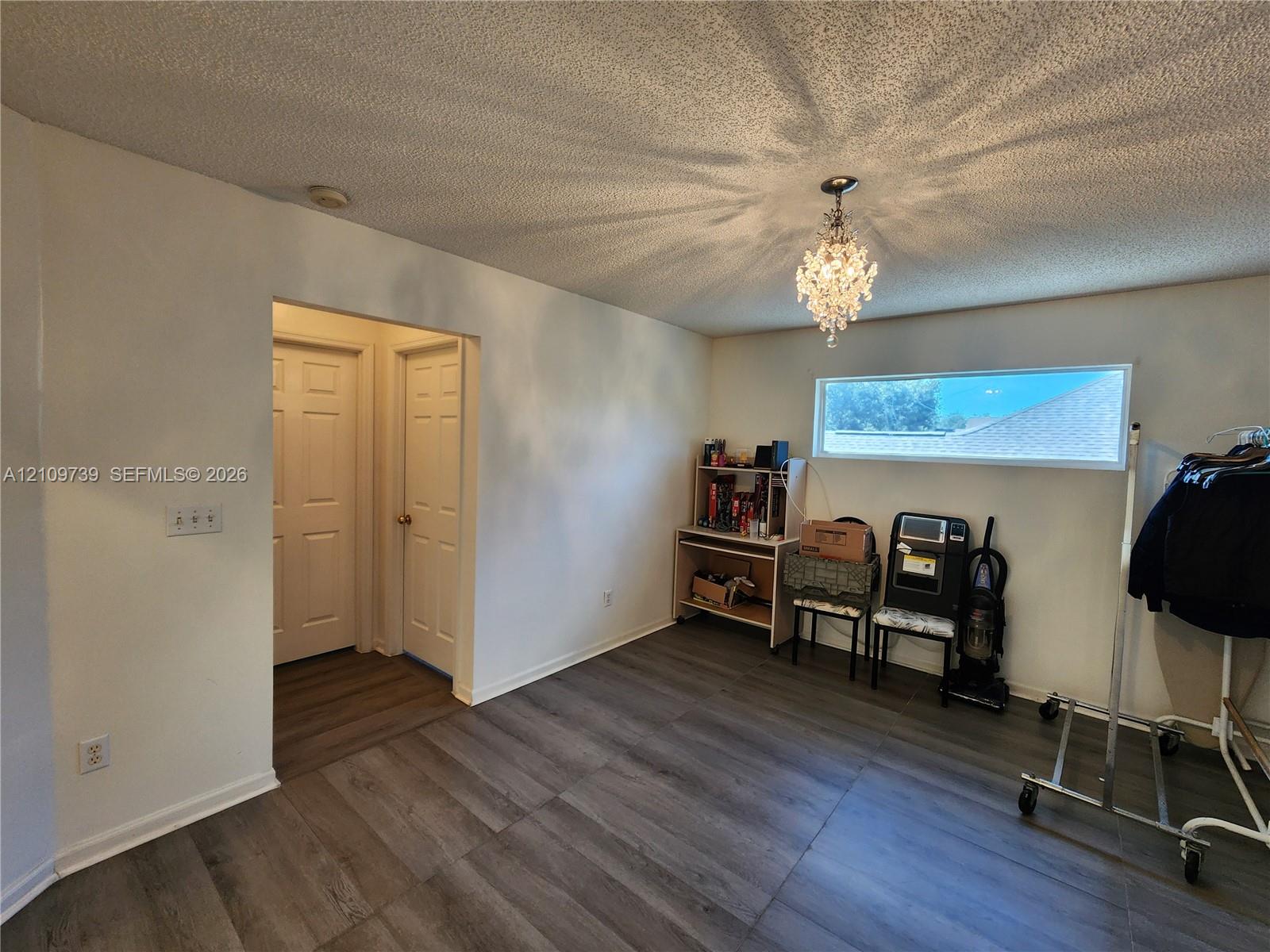 Wood-finish flooring, crystal-style chandelier, horizontal window, and paneled doors