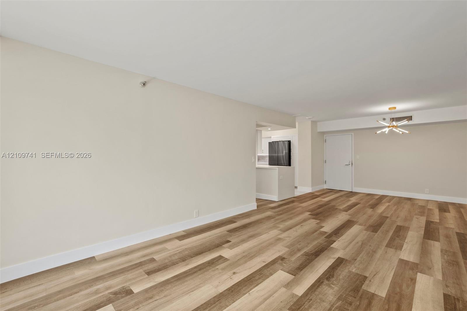 Open-concept interior featuring wood-finish plank flooring, neutral wall tones, and a modern sputnik-style chandelier