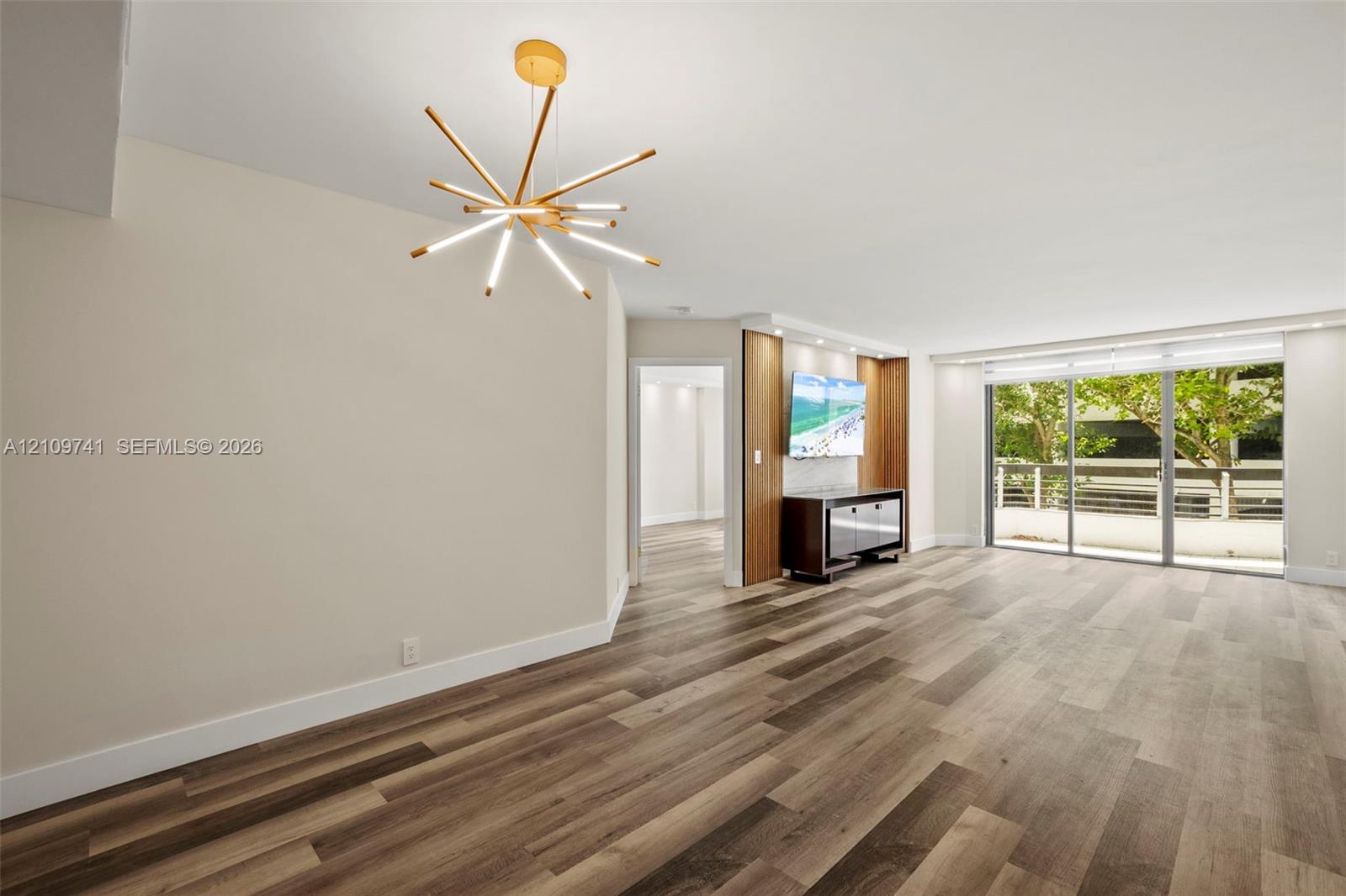 Wood-finish flooring, multi-arm contemporary pendant light, custom built-in cabinetry with integrated accent lighting, and expansive sliding glass doors Wood-finish flooring, multi-arm contemporary pendant light, custom built-in cabinetry with integrated accent lighting, and expansive sliding glass doors